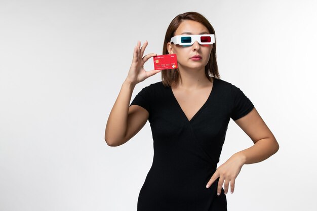 Вид спереди молодая женщина, держащая банковскую карту в солнцезащитных очках d на белой поверхности