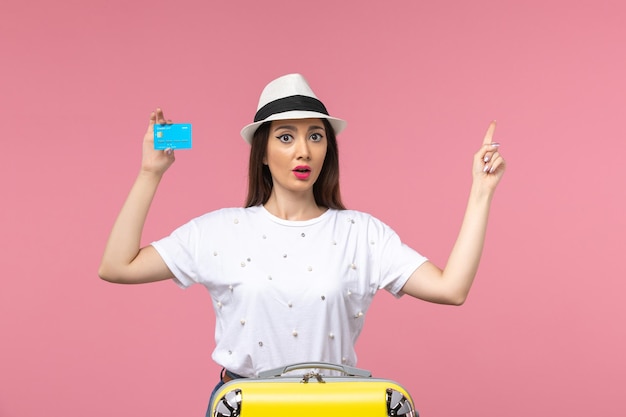 Front view young female holding bank card on light-pink wall woman trip summer emotion