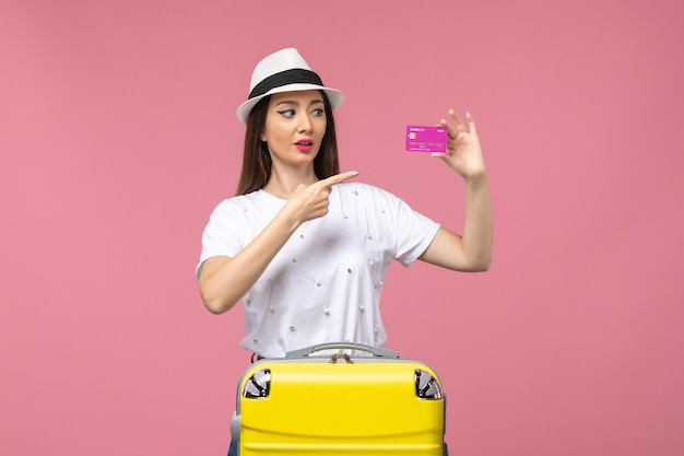 Front view young female holding bank card on pink desk trip woman vacation money