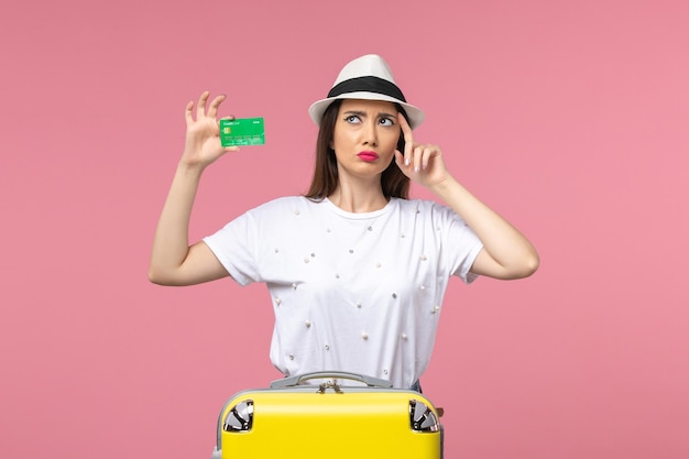 ピンクの壁の感情の夏の女性の旅行で銀行カードを保持している正面図若い女性