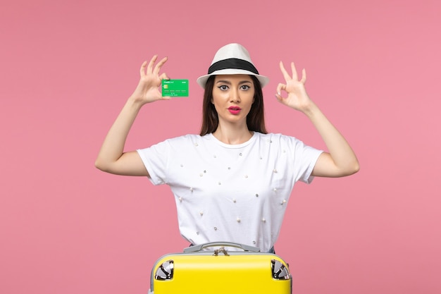 Front view young female holding bank card on pink wall summer trip emotions woman