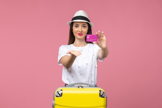 Front view young female holding bank card on the pink wall trip vacation woman money