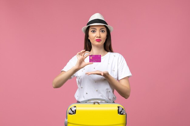 Front view young female holding bank card on pink wall trip woman vacation money