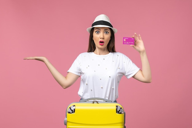 Front view young female holding bank card on pink wall vacation money woman trip