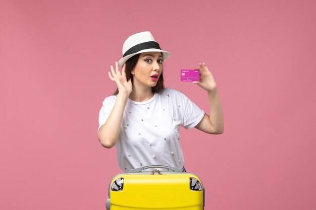 Front view young female holding bank card on pink wall vacation woman trip money