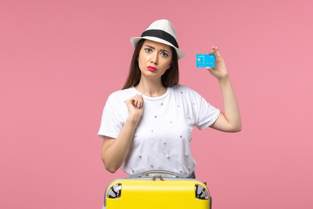 Front view young female holding bank card on the pink wall woman trip summer emotion