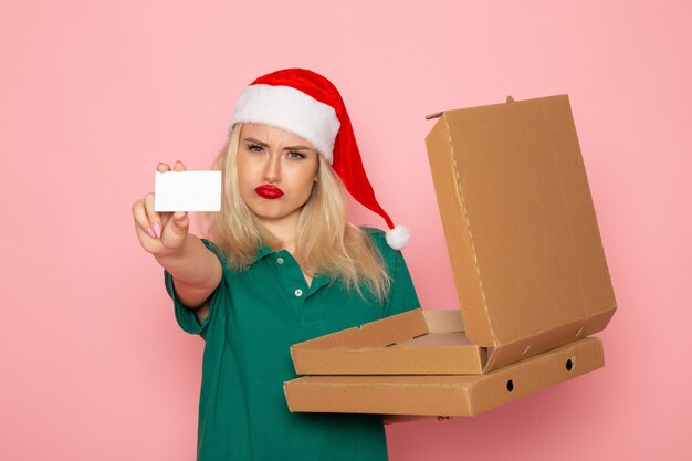 분홍색 벽 색상 휴일 크리스마스 새해 사진 작업 유니폼에 은행 카드와 피자 상자를 들고 전면보기 젊은 여성