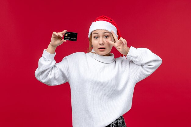 赤い背景に銀行カードを保持している若い女性の正面図
