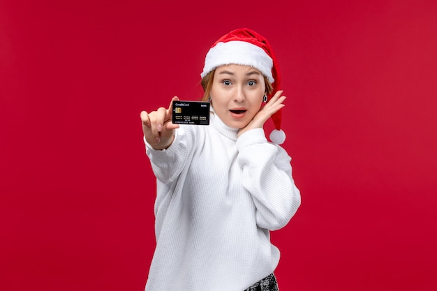 Front view young female holding bank card on red background