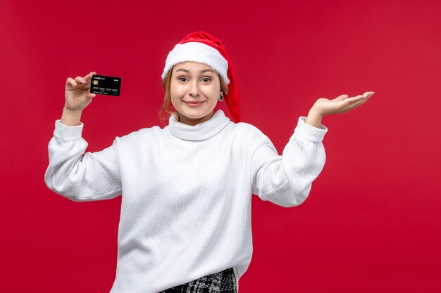 Front view young female holding bank card on red background