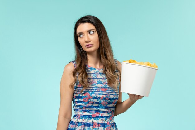 Front view young female holding basket with chips on blue surface