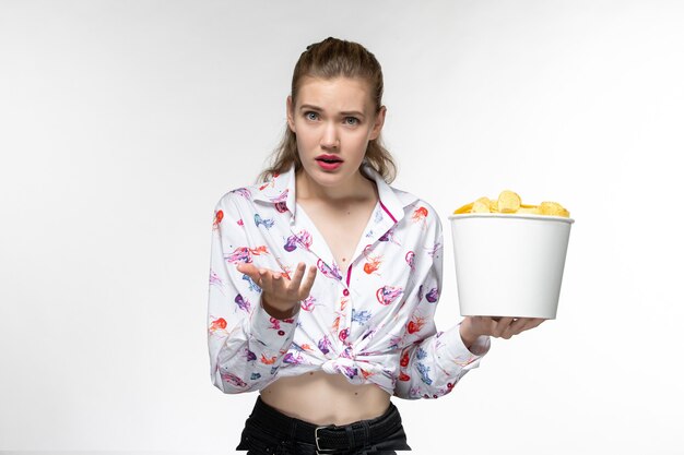 Front view young female holding basket with chips on light surface