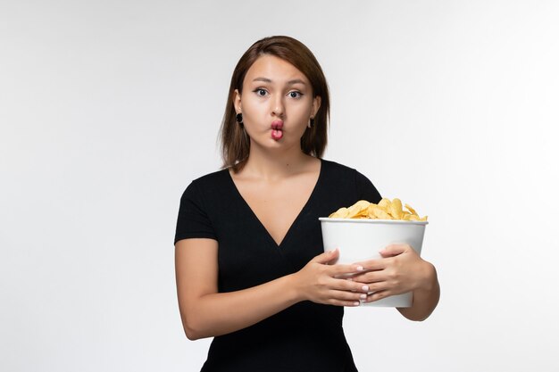 Front view young female holding basket with chips and making funny expression on white surface