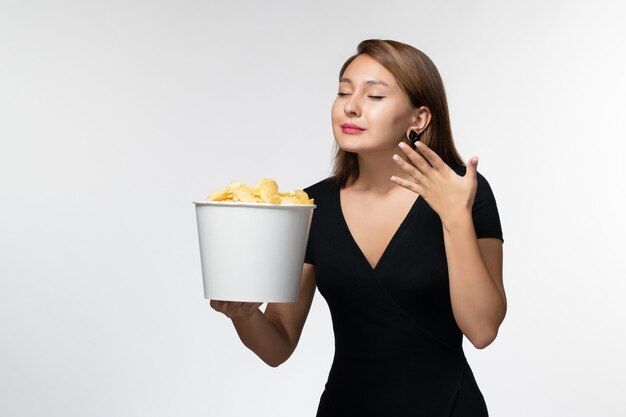 Front view young female holding basket with chips and smelling on white surface