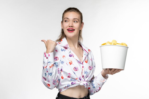 Front view young female holding basket with chips and smile on white surface