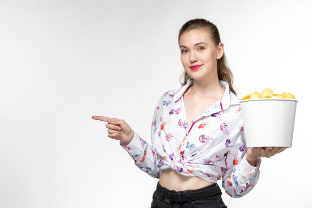 Front view young female holding basket with chips smiling on white surface