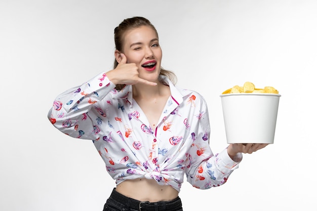 Free photo front view young female holding basket with chips on the white surface