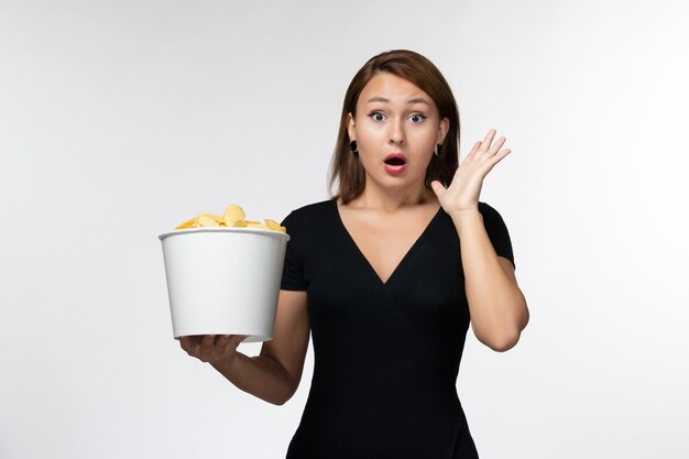 Front view young female holding basket with potato chips and shocked on white surface