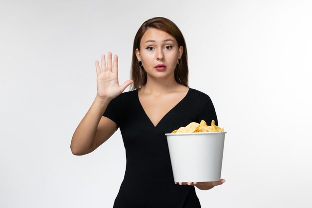 Front view young female holding basket with potato chips and watching movie on white desk