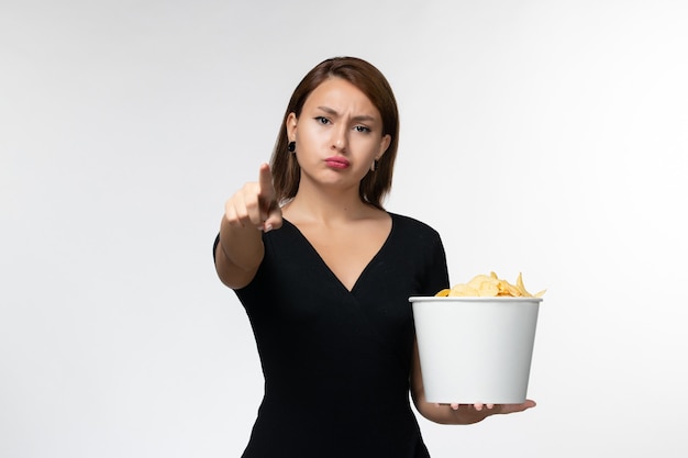 Free photo front view young female holding basket with potato chips and watching movie on white surface