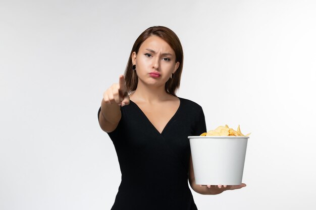 Front view young female holding basket with potato chips and watching movie on white surface