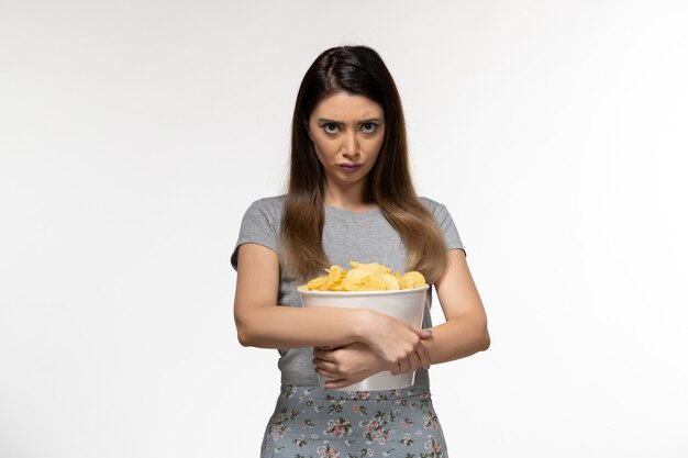 Front view young female holding basket with potato chips on the white desk