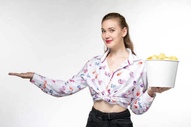 Front view young female holding basket with potato chips on a white surface