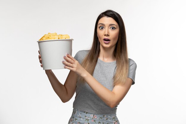 Front view young female holding basket with potato chips on white surface