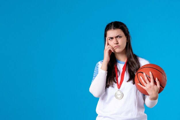 Front view young female holding basketball on blue wall