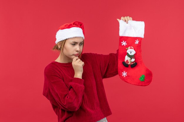 赤い床の赤いクリスマスの休日に大きなクリスマスの靴下を保持している正面図若い女性