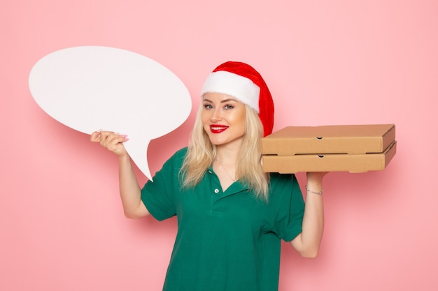 Front view young female holding big white sign and food boxes on pink wall photo work uniform new year holiday job courier