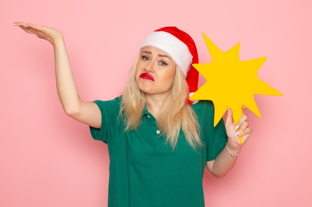 Front view young female holding big yellow figure on a pink wall holiday photo new year courier uniform job work