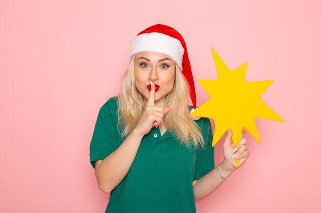 Front view young female holding big yellow figure on a pink wall photo work new year holiday job courier uniform