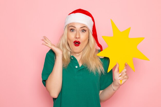 Front view young female holding big yellow figure on pink wall photo work new year holiday job courier