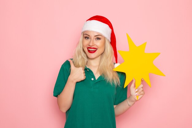 Front view young female holding big yellow figure on pink wall photo work new year holiday job uniform