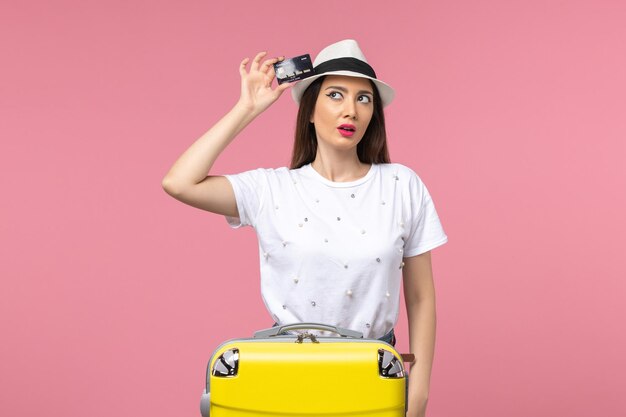 Front view young female holding black bank card on pink wall trip color voyage