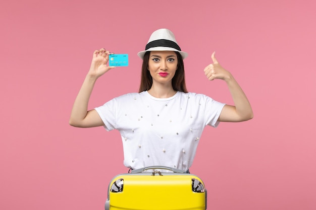 Front view young female holding blue bank card on a pink wall trip voyage woman money