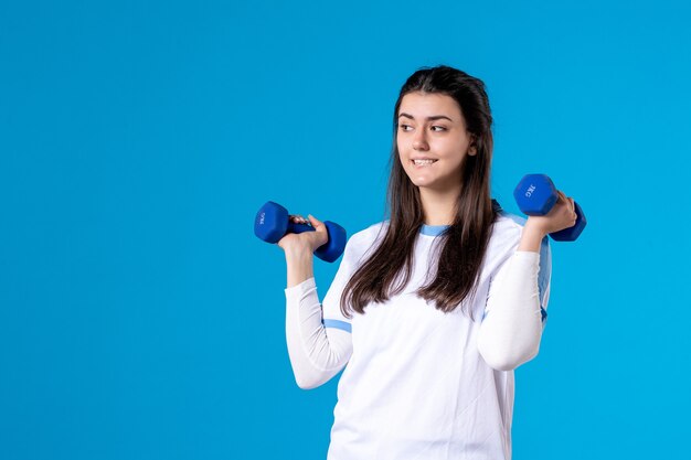 Front view young female holding blue dumbbells