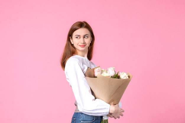 Front view young female holding bouquet of beautiful roses on pink