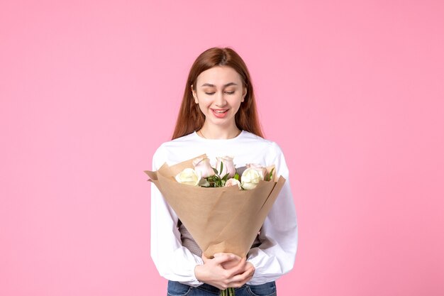 Front view young female holding bouquet of beautiful roses on pink