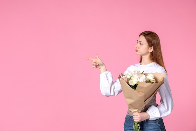 Front view young female holding bouquet of beautiful roses on pink