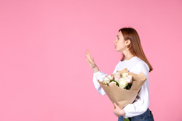 분홍색에 아름 다운 장미 꽃다발을 들고 전면 보기 젊은 여성