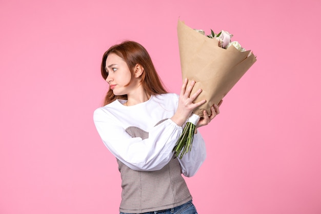 Бесплатное фото Вид спереди молодая женщина держит букет красивых роз на розовом
