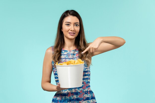 Front view young female holding chips on the blue surface