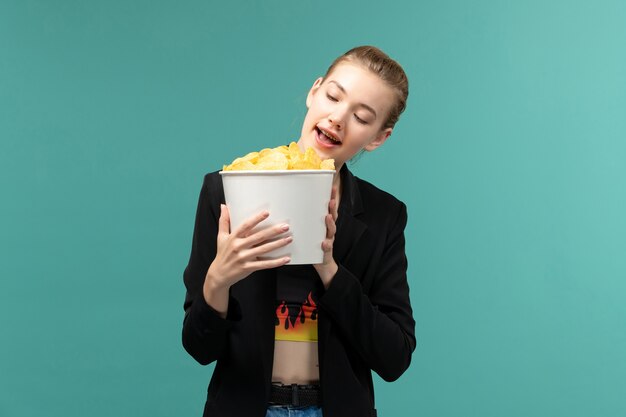 Front view young female holding chips and watching movie on blue surface