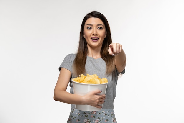 Front view young female holding chips and watching movie on the white surface