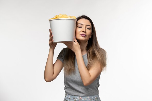 Front view young female holding chips and watching movie on white surface