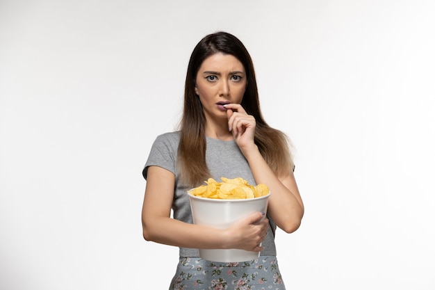 Front view young female holding chips and watching movie on white surface