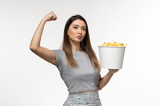 Front view young female holding chips while watching movie flexing on white surface