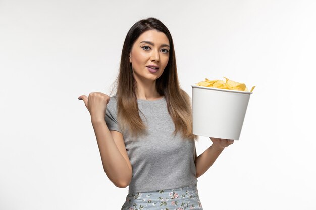 Front view young female holding chips while watching movie on white desk